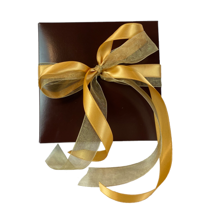 A rick chocolate colored gift box wrapped in gold sating and sheer ribbon